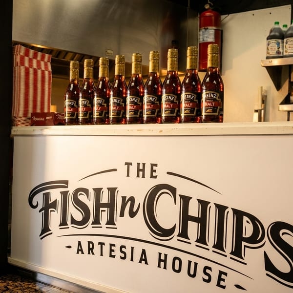 The Fish 'n Chips Artesia House counter with malt vinegar bottles and payment options.