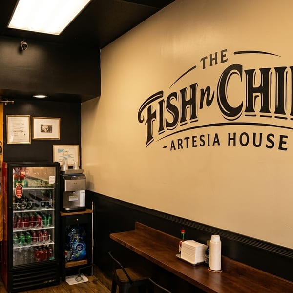 Interior of The Fish n' Chips Artesia House with a large logo on the wall and seating.